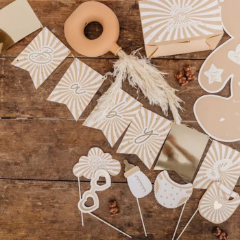 Guirlande de fanions beige et crème pour baby shower avec motifs rayonnants, accessoires décoratifs et toppers sur bois.