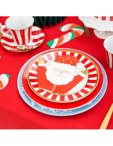 Assiette décorative de Noël avec Papa Noël sur fond rouge et assiettes festives, décor candy cane et vaisselle assortie.