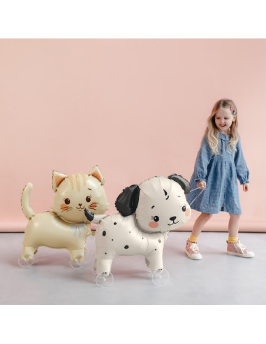 Katzenballon auf Rädern: kleines Mädchen in blauem Kleid zieht zwei ballonierte Katzen mit Rädern, hellbeige und weiß mit schwar